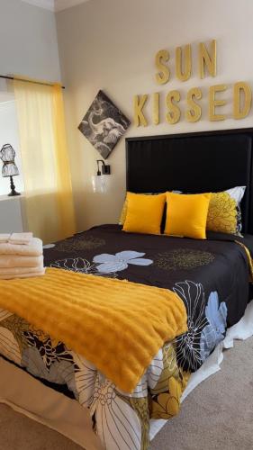 a bedroom with a bed with a yellow blanket on it at Sun-Kissed Stays in Galveston