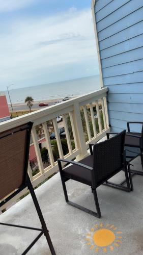 a balcony with two chairs and a view of the ocean at Sun-Kissed Stays in Galveston