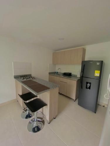 Una cocina con encimera, refrigerador y taburete. en Apartamento en Manizales, en Manizales