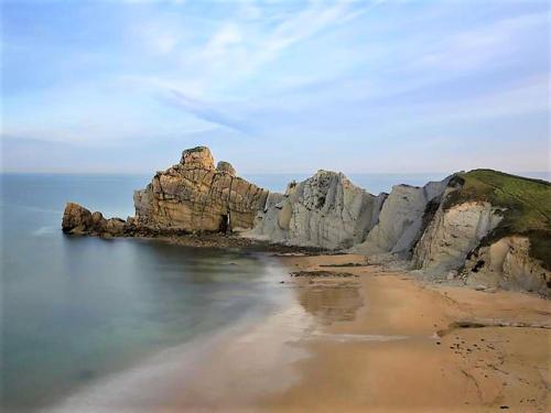 a large rock formation in the water with a beach at Holiday Home in Loredo near Surf Beach in Loredo