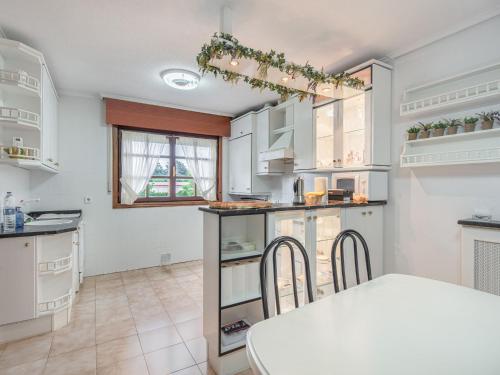 a kitchen with white cabinets and a table and chairs at Holiday Home in Loredo near Surf Beach in Loredo