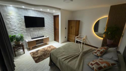 une chambre avec un lit et une télévision sur un mur dans l'établissement Flats do Cabo e Suítes, à Arraial do Cabo