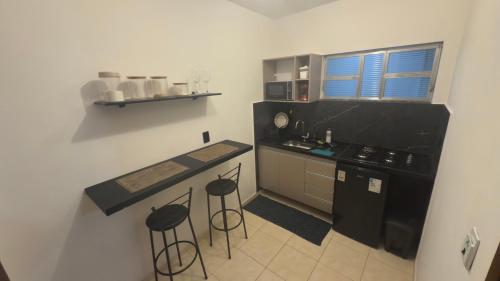 - une petite cuisine avec un comptoir et des tabourets dans l'établissement Flats do Cabo e Suítes, à Arraial do Cabo