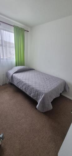 a bed in a bedroom with a green curtain at Casa villa los regidores 01 in Vallenar