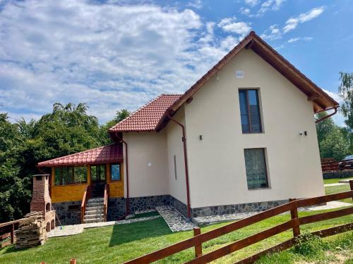 a small white house with a wooden fence at Vila Eden Pestera in Peştera