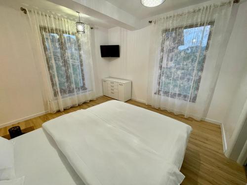 a white bed in a room with two windows at Vila Eden Pestera in Peştera