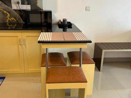 a kitchen with a table with two stools and a microwave at High Tides at Ocean Breeze in Negombo