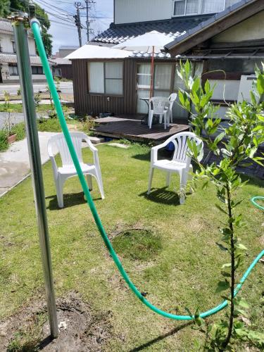 a garden with two chairs and a green hose at Guesthouse ONE WORLD 一棟貸の宿 in Kitsuki