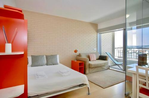 a bedroom with a bed and a chair and a balcony at Oporto Blue Dragão - Modern Uptown Studio With Free Parking in Porto