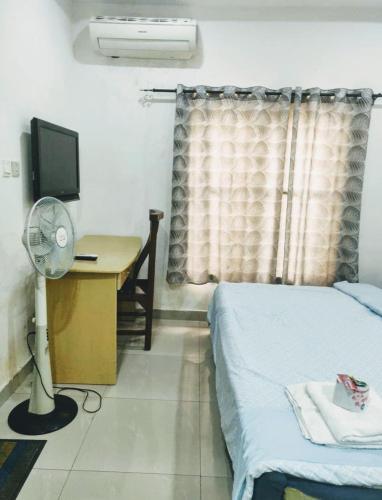 a bedroom with a bed and a desk with a television at st theresas homes in Lagos