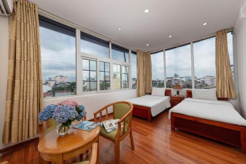 ハノイにあるPhoenix Palace Hotel Hanoiのベッド2台、テーブル(花付)が備わる客室です。