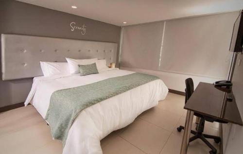 una camera da letto con un grande letto bianco e una scrivania di Serenity by noa hotels a Bogotá