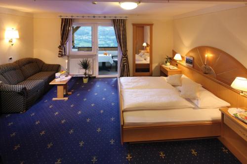 a hotel room with a large bed and a couch at Sonnenhotel Adler Spa & Nature Adults only in Villandro