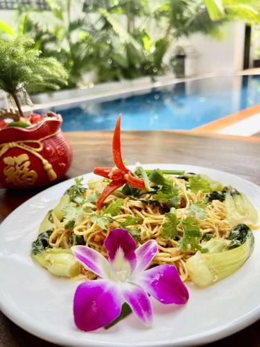 a plate of food with a purple flower on a table at Pride Villa Cambodia in Phnom Penh
