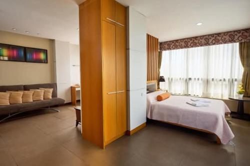 a hotel room with a bed and a couch at Fuente Oro Business Suites Cebu in Cebu City