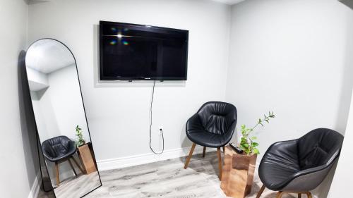 a living room with two black chairs and a mirror at 2 Bedroom Walkout Basement Ajax in Ajax
