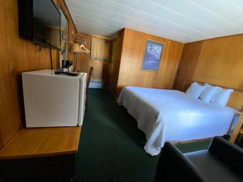 a bedroom with a white bed and a television at Trails end motel in Dubois