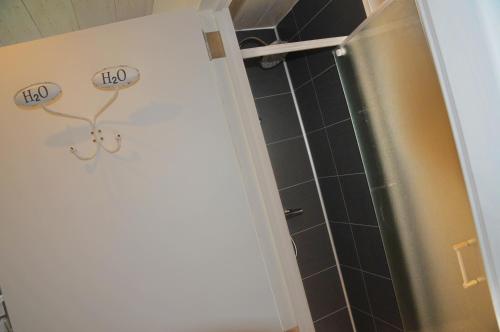La salle de bains est pourvue d'une douche et d'une porte avec deux verres. dans l'établissement Chalet d'Aventures, à Durbuy