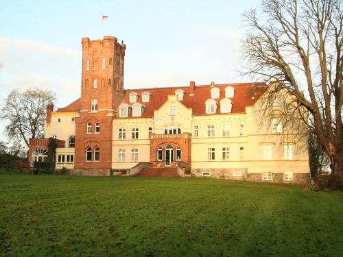 un gran edificio con una torre en lo alto de un campo en Schloss Lelkendorf, Fewo Hoppenrade, en Lelkendorf