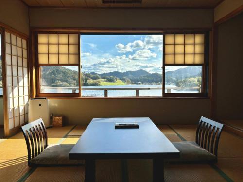 a table and two chairs in a room with windows at 純和風旅亭 碧翠御苑 in Kyotango