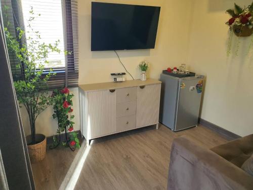 a living room with a refrigerator and a television on the wall at Nordika Hill in Pak Chong