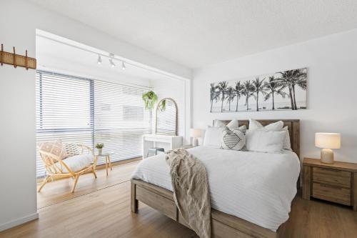 a white bedroom with a bed and a chair at LOCATION, LOCATION! Walk to anywhere! in Gold Coast