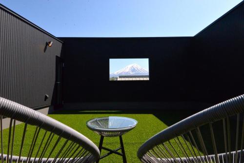 a room with two chairs and a table and a mountain at 61 Fuji Petel UN -アン- in Fujikawaguchiko