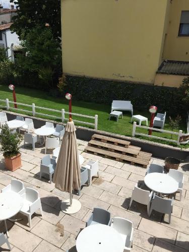a patio with tables and chairs and an umbrella at Albergo Al Cacciatore Tortellinando in Valeggio sul Mincio