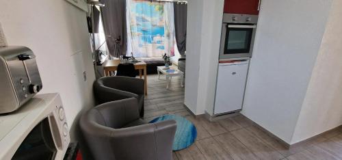 a living room with two chairs and a kitchen at Comfortable studio in Bevaix with mountain view - 30 m² + Spa in Bevaix