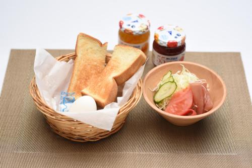 a basket of bread and a bowl of salad and a sandwich at Hotel YAN-NEKO in Hirakata