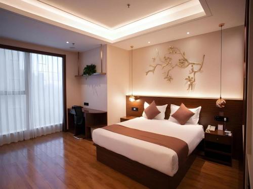 a hotel room with a large bed and a desk at Gya Hotel Tangshan Qian'an Fortune Center in Qian'an