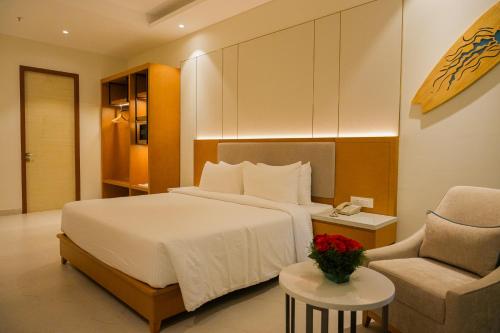 a hotel room with a bed and a chair at The Shore Trishvam in Puducherry