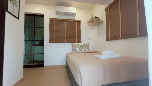 a bedroom with a bed in a room with windows at Nordika Hill in Pak Chong