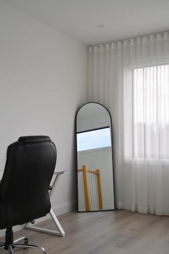 a mirror sitting next to a chair in a room at Entire House Stay in Springvale in Springvale