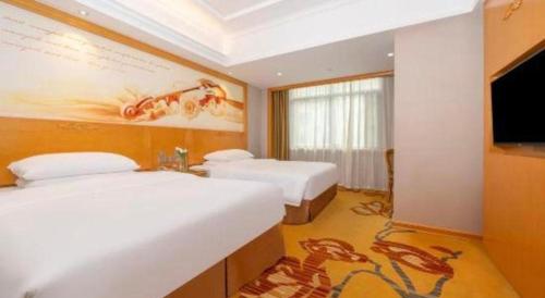 a hotel room with two beds and a flat screen tv at Vienna Hotel Guangxi Fangcheng in Fangcheng