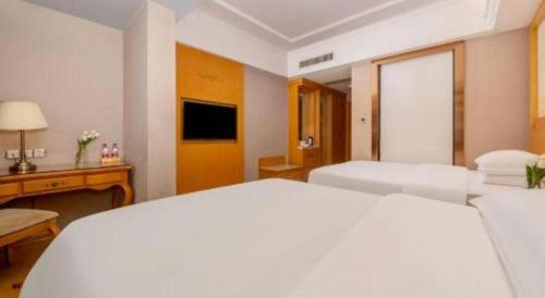 a white bedroom with two beds and a desk at Vienna Hotel Guangxi Fangcheng in Fangcheng