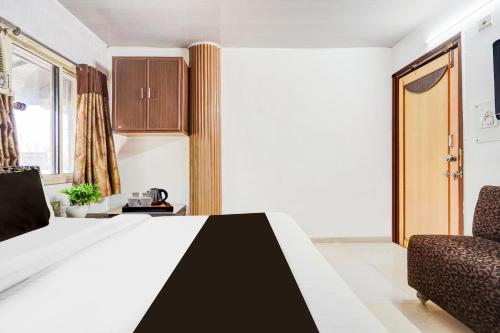 a bedroom with a bed and a chair at Super Collection O Maninagar East Formerly Maninagar Residency in Ahmedabad