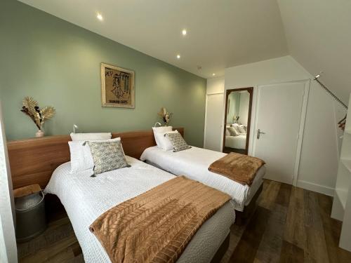 two beds in a small room with a mirror at Arbor & Sens in Languidic