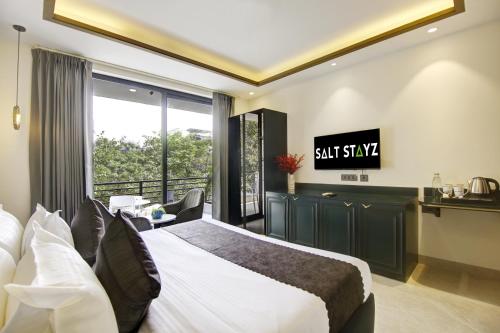 a hotel room with a bed and a desk and a window at Saltstayz Premier - Galleria Market Road & Sector 27 in Gurgaon