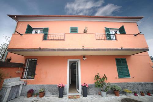 una casa arancione con persiane verdi e piante in vaso di B&B Agorà Sarzana a Sarzana