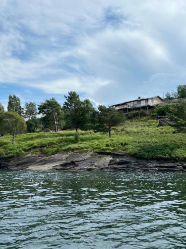 a house on a hill next to a body of water at Turer, avslapping, jakt, fiske, utsikt in Etnesjøen