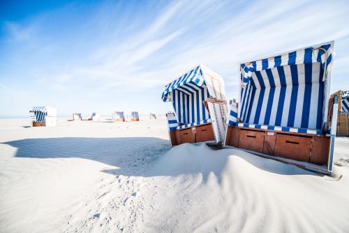 two beach chairs sitting in the sand on the beach at Hotel Zweite Heimat in Sankt Peter-Ording