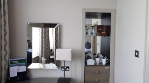 a room with a mirror and a lamp and a dresser at Crown & Mitre Hotel in Carlisle