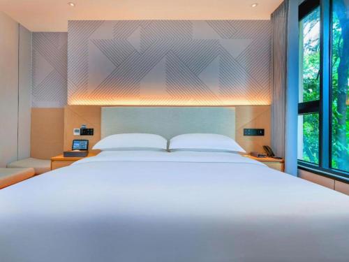 a bedroom with a large white bed and a window at Borrman Hotel Chongqing Bishan Central Street in Chongqing