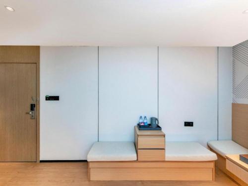 a bedroom with white walls and a wooden bench at Borrman Hotel Chongqing Bishan Central Street in Chongqing