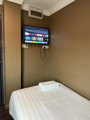 a bedroom with a bed and a tv on the wall at HOTEL JJH Aliwal in Singapore