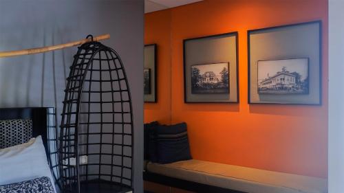 a bedroom with an orange wall with a bench and pictures at Mercure Surabaya Grand Mirama in Surabaya