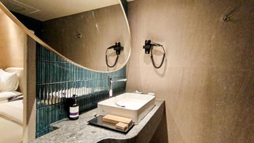 a bathroom with a sink and a mirror at Mercure Surabaya Grand Mirama in Surabaya