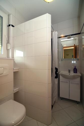 a white bathroom with a toilet and a sink at Apartments Ćorić in Baška Voda