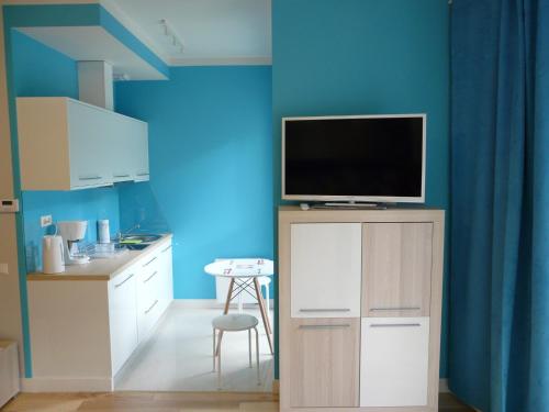 a kitchen with blue walls and a tv on a cabinet at Apartament Bluesky in Świnoujście